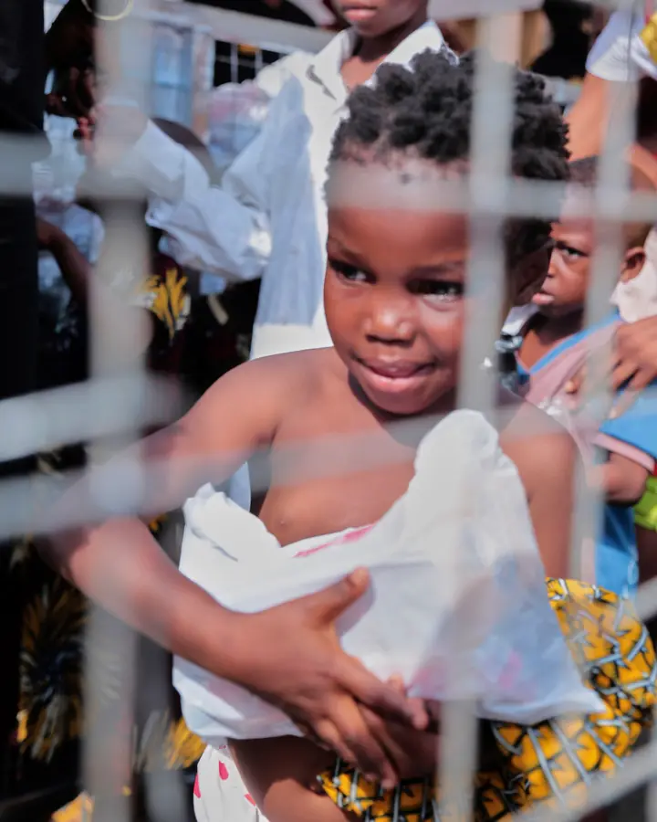 A young child holding a food pack beside a barrier