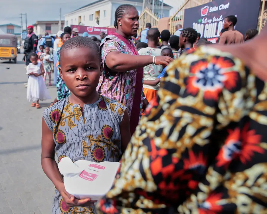 Children smiling and holding food packs at a Sábi Chẹf event