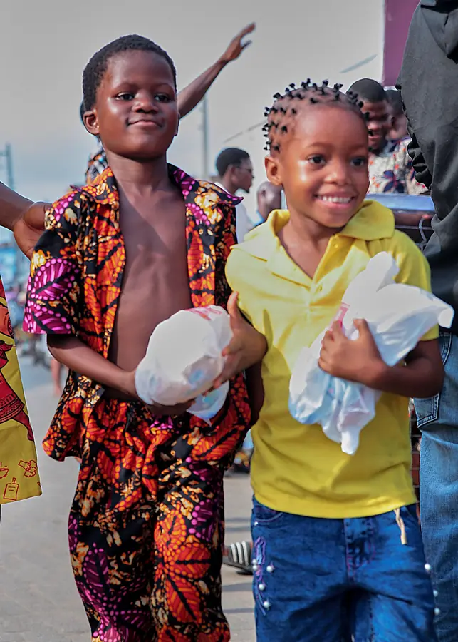 Two smiling children holding their meal packs at a Sábi Chẹf event